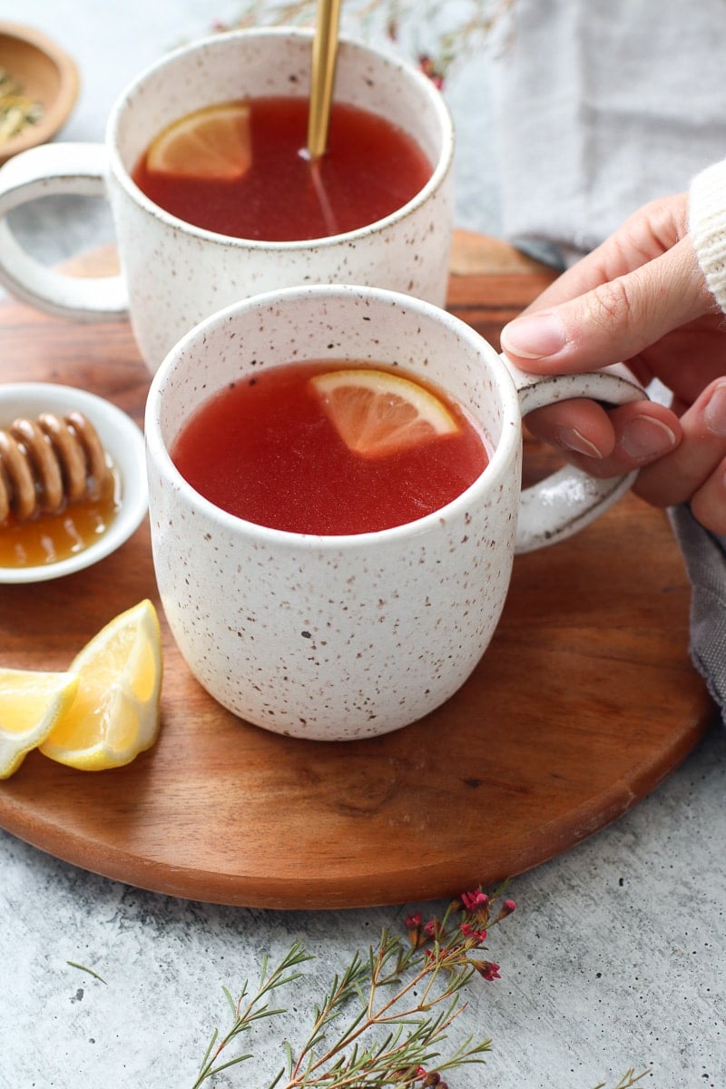 A hand lifting a mug of Starbucks Medicine Ball Tea off a wooden tray.