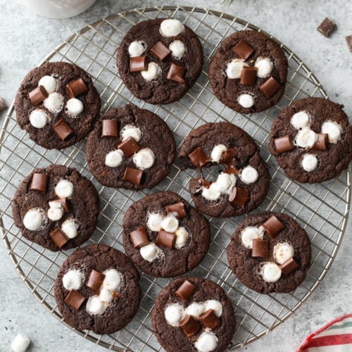 Round wire rack filled with Mexican hot chocolate cookies topped with melted mini marshmallows and chocolate chunks.