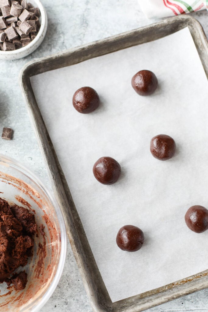 Mexican hot chocolate cookie dough balls lined up on parchment covered baking sheet.