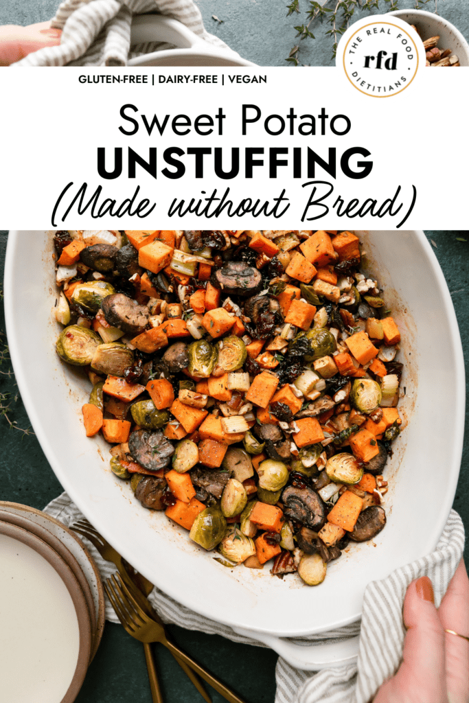 Two hands holding a white casserole dish filled with sweet potato unstuffing, topped with pecans, cranberries, and mushrooms.