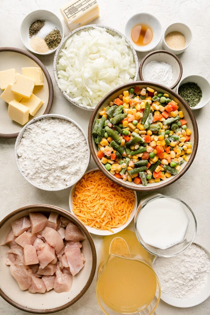 All ingredients for chicken pot pie casserole arranged together in bowls.