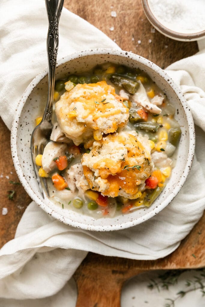 Serving of chicken pot pie casserole in a stone bowl topped with a cheddar biscuit