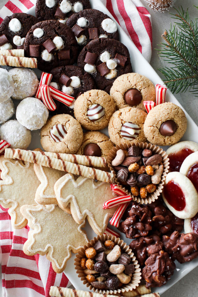 White tray filled with assortment of Christmas cookies and treats on a red and white striped dish cloth.