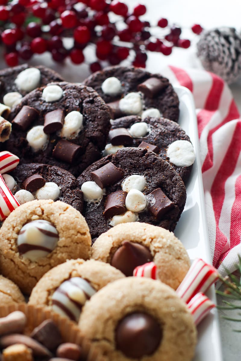 Close up view Mexican hot chocolate cookies and peanut butter blossom cookies on a white tray.