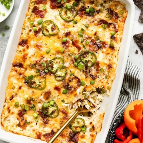 Jalapeño Popper Dip in white baking dish topped with melted cheese.