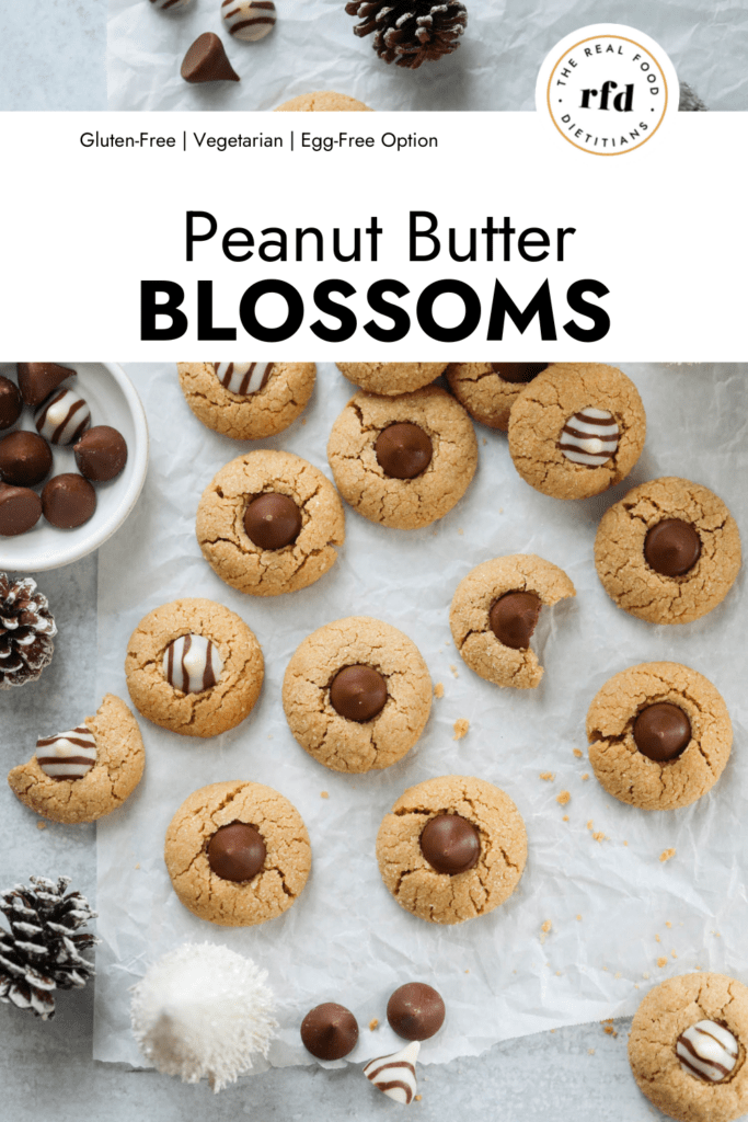 Overhead view several peanut butter blossoms with chocolate kisses in centers arranged together on parchment paper.