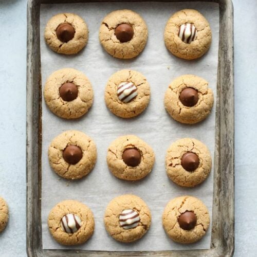 Overhead view baking sheet filled with lined up peanut butter blossom cookies.