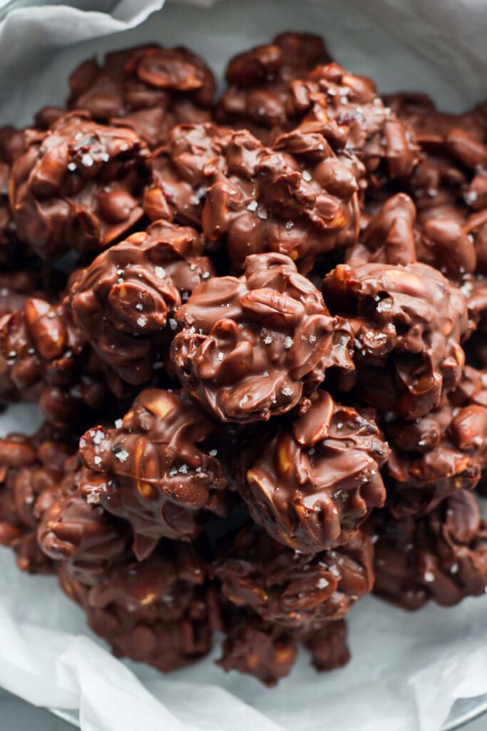 Close up overhead view peanut butter chocolate clusters in a pile, sprinkled with sea salt.