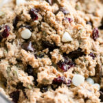 Close up view trail mix breakfast cookie batter in clear glass mixing bowl.