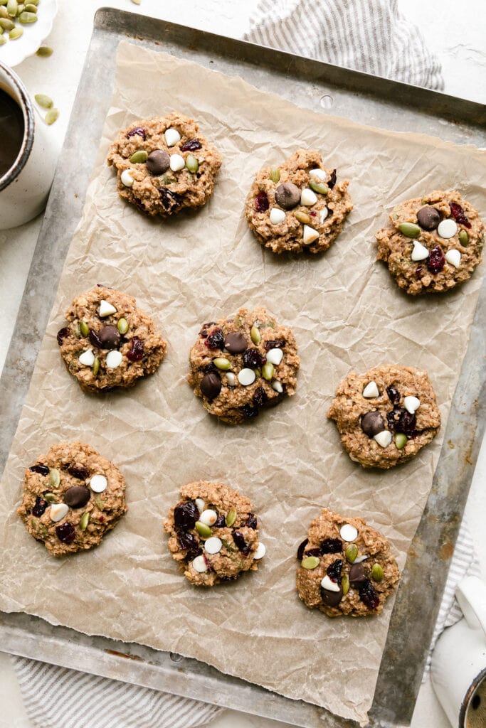 Overhead view parchment paper lined cookie sheet with lined up trail mix breakfast cookies.