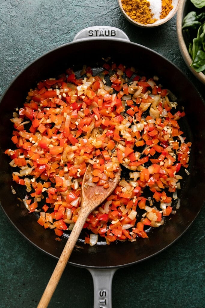 Process shot, cast iron skillet with sautéed red bell pepper and onions.