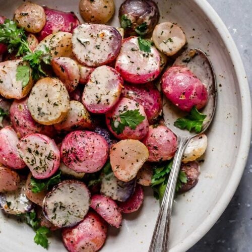 Garlic roasted radish halves coated in ranch dressing on stone plate.