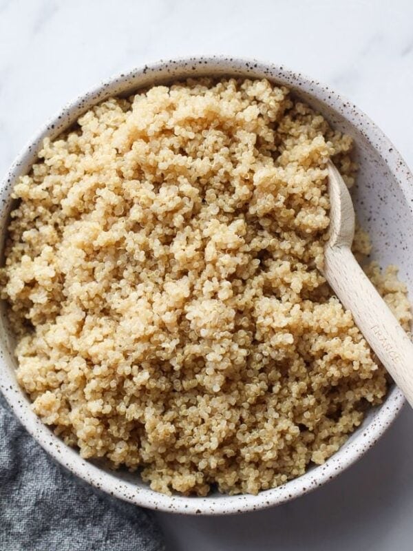 Cooked quinoa in stone bowl with wooden spoon