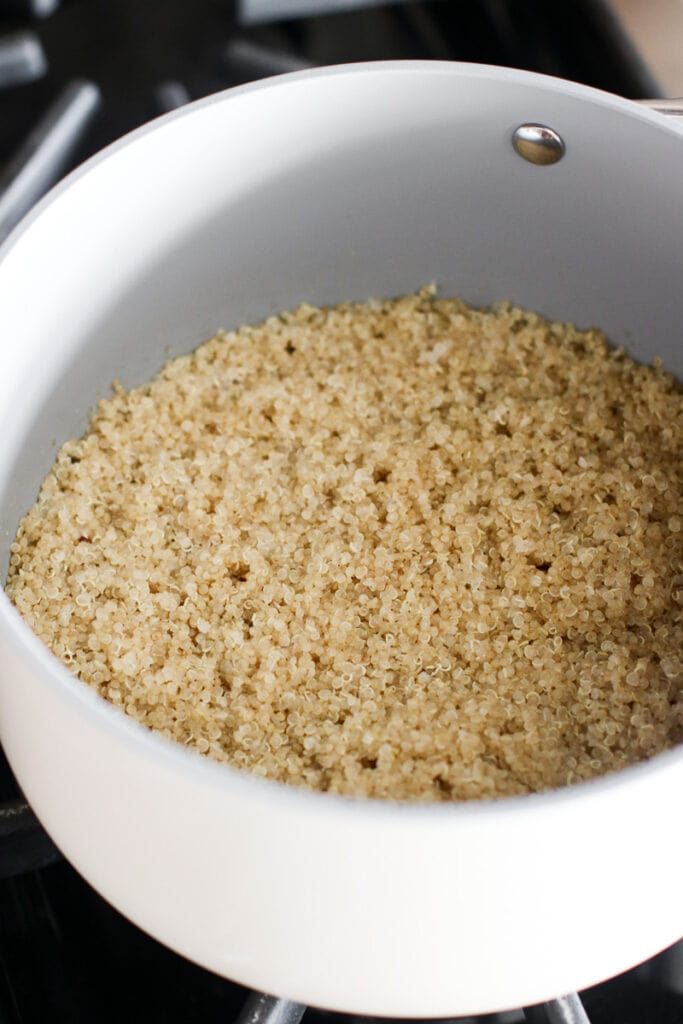 Cooked quinoa in a white saucepan on stovetop
