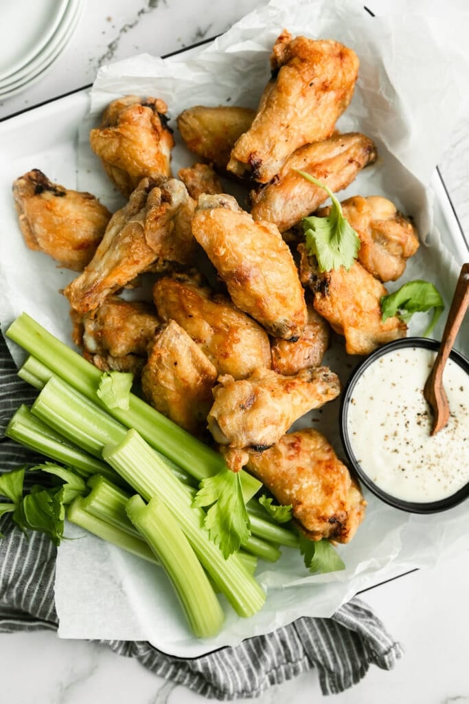 Golden brown cooked and crispy air fryer chicken wings with ranch dipping sauce and celery 