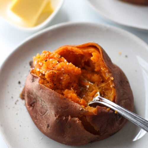 Overhead view instant pot sweet potato cut open, sprinkled with sea salt and pepper, fork in sweet potato