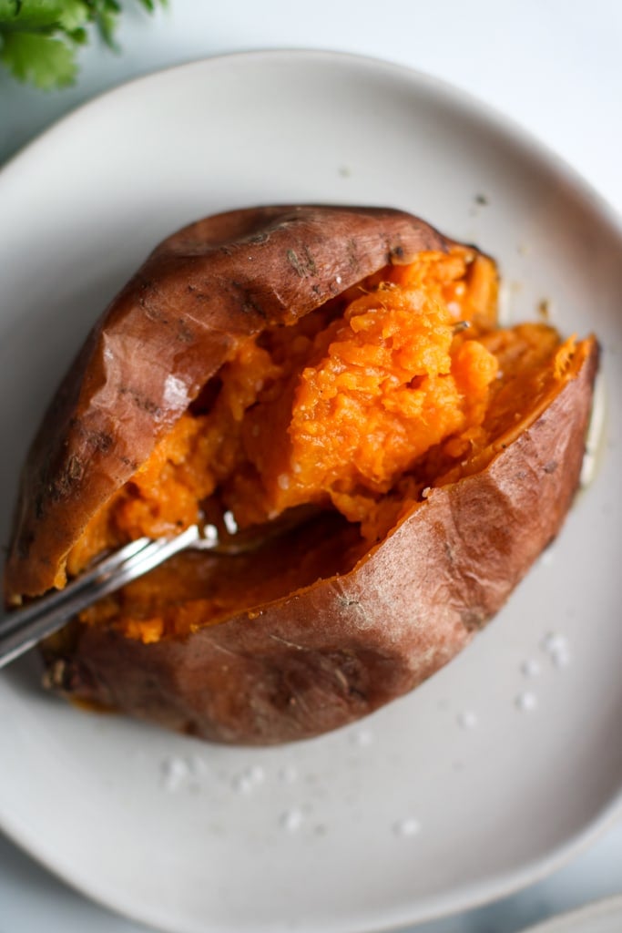 A baked sweet potato, cut open to show orange fluffy inside