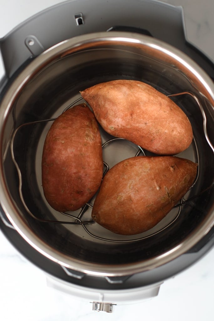 Three medium sweet potatoes in an instant pot on a trivet.