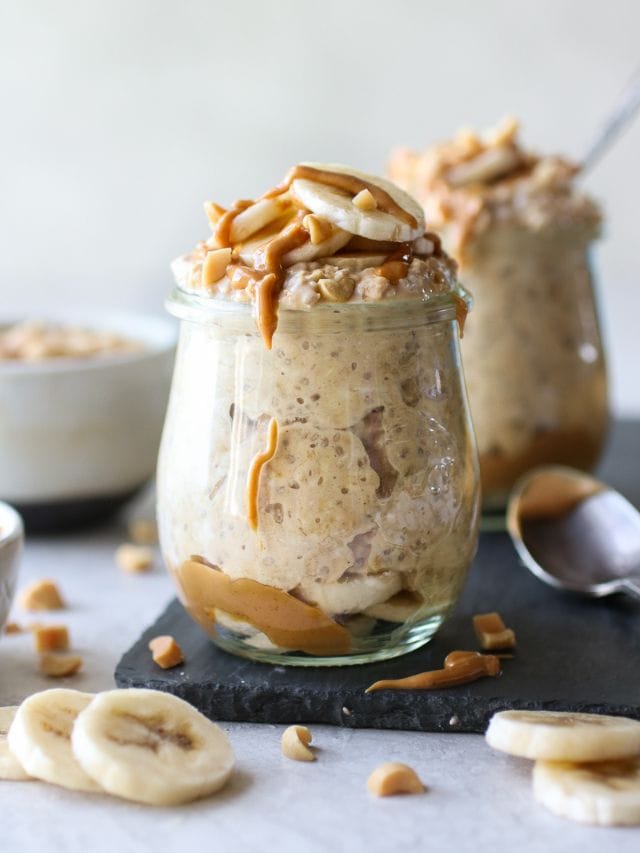 Peanut butter banana overnight oats in small glass jars topped with banana slices and drizzled with peanut butter