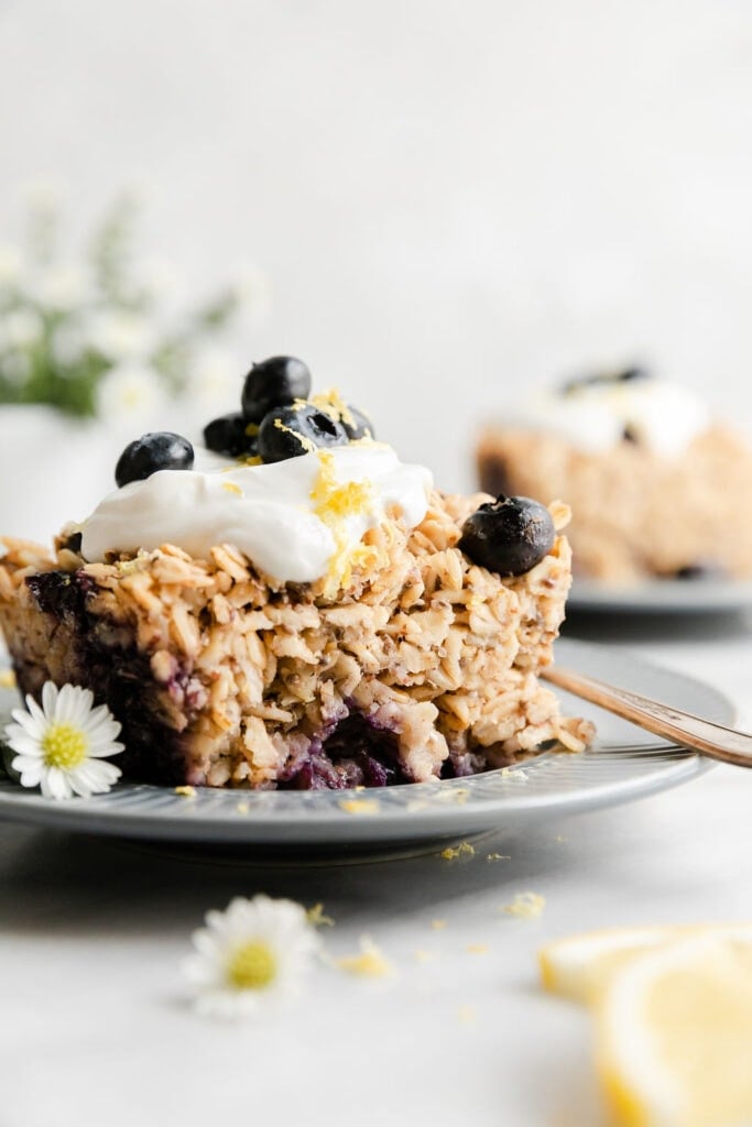 Side view blueberry lemon baked oatmeal on plate topped with yogurt and lemon zest.