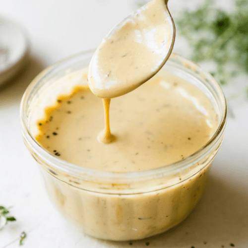 Honey mustard sauce dripping from spoon into bowl