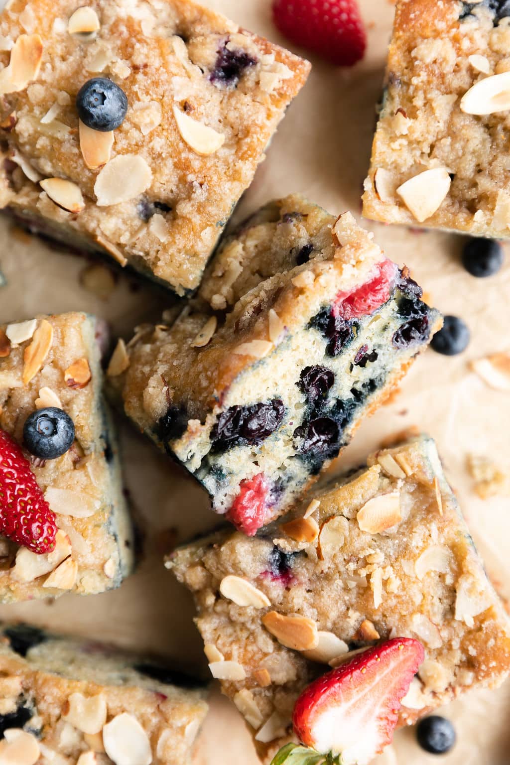 Mixed berry breakfast cake with crumb topping cut into squares arranged together with one square on side to show layers.
