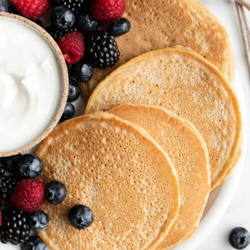 Protein pancakes on plate with fresh berries and yogurt.