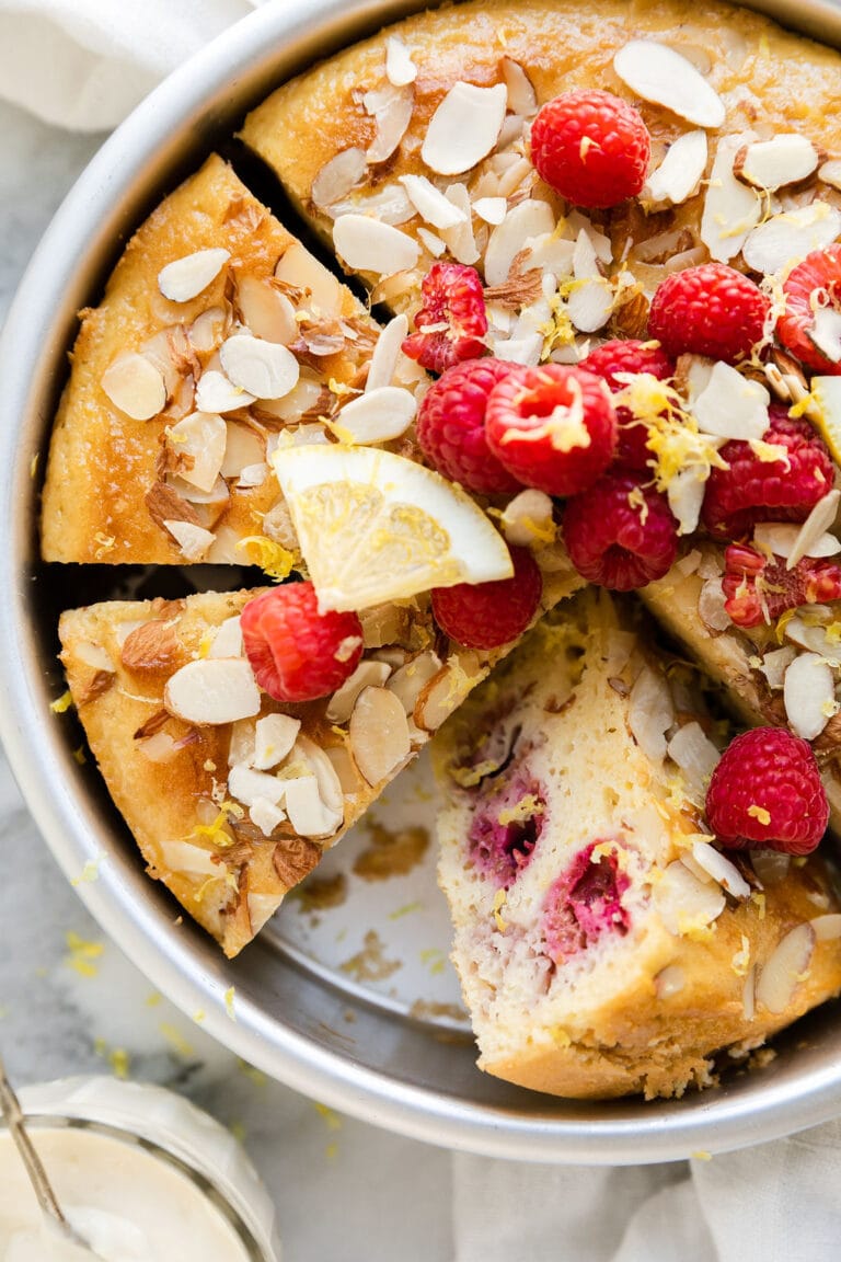 A pan of freshly baked raspberry lemon coffee cake topped with lemon zest and fresh raspberries. 