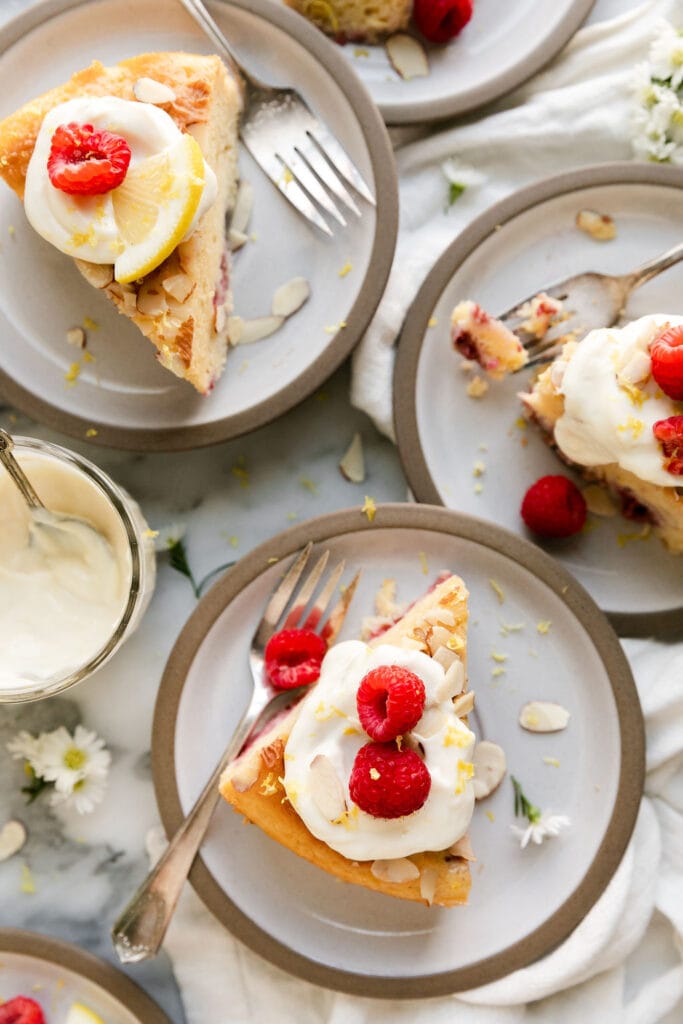 Several plated raspberry lemon coffee cake slices topped with lemon sour cream and almonds.