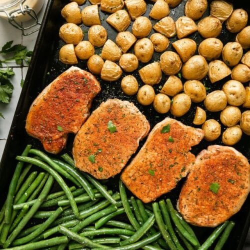 Overhead view sheet pan filled with pork chops, potatoes, and green beans.