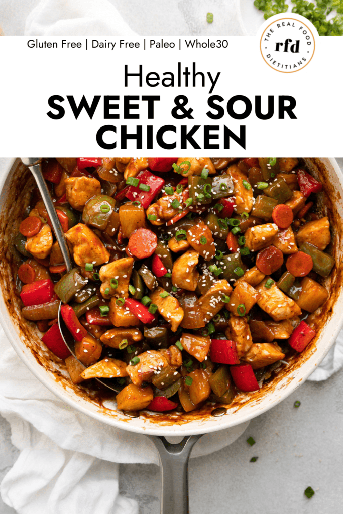 Skillet filled with healthy sweet and sour chicken, sprinkled with sesame seeds.