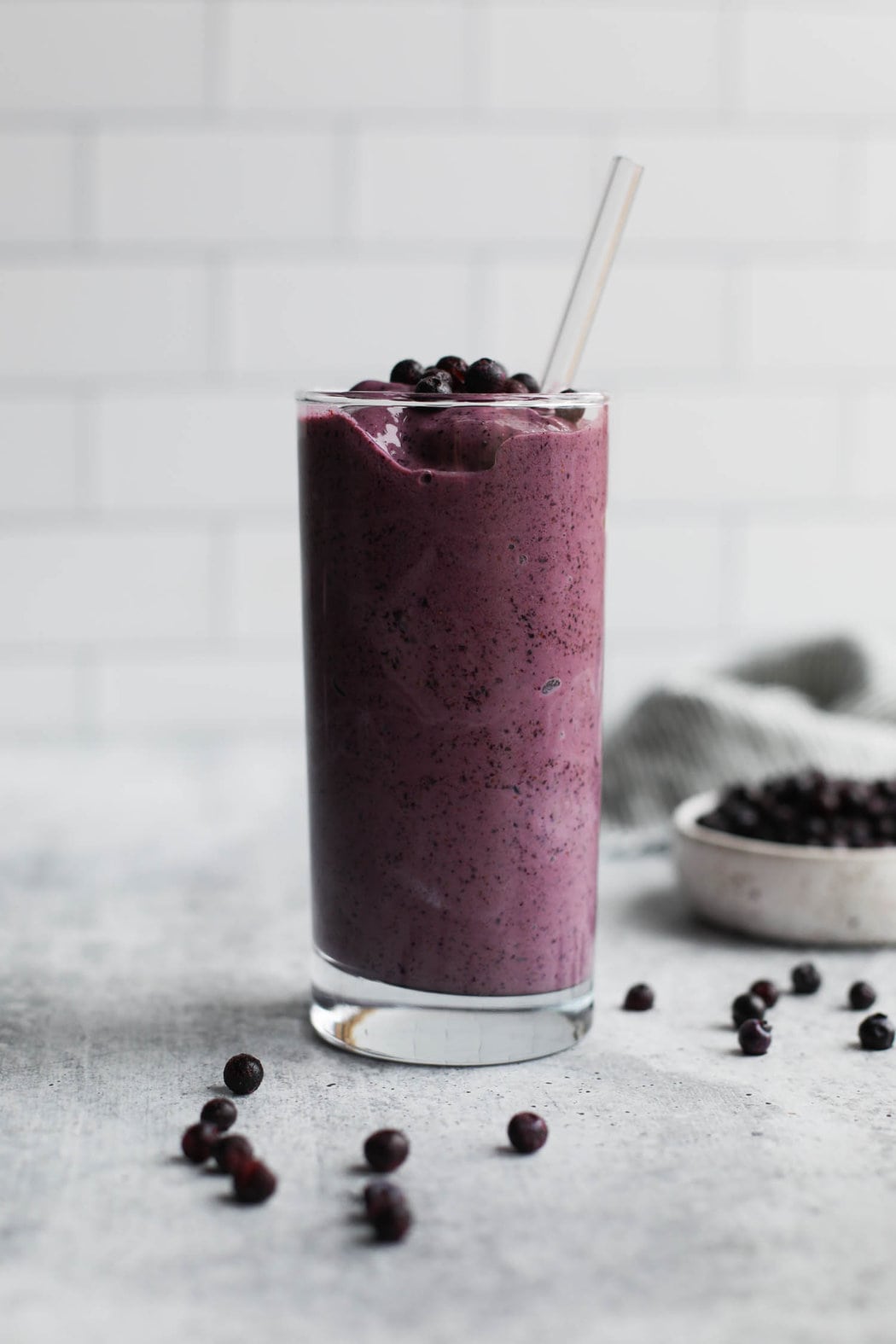 Side view tall clear glass filled with wild blueberry smoothie