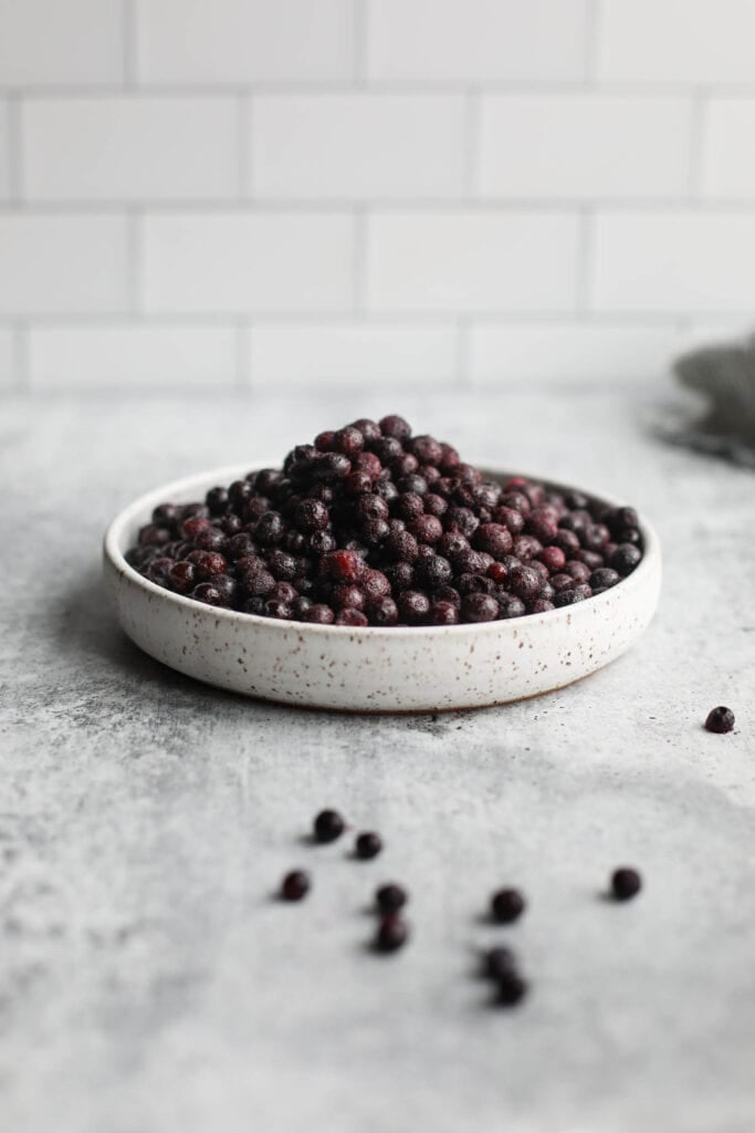 Side view stone bowl piled high with wild blueberries.