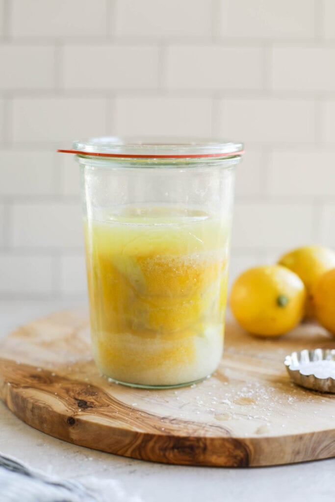 Close up view of a class container filled with fermented lemons. 