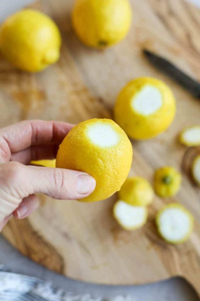 A hand holding a lemon with the end trimmed off.