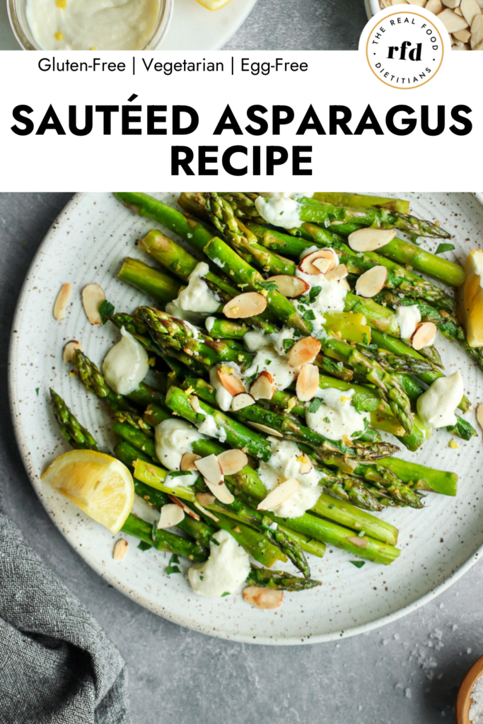 Sauteed asparagus with goat cheese sauce, almonds, and lemons, on stone plate.