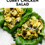 Two lettuce leaves filled with curry chicken salad topped with raisins and cashews