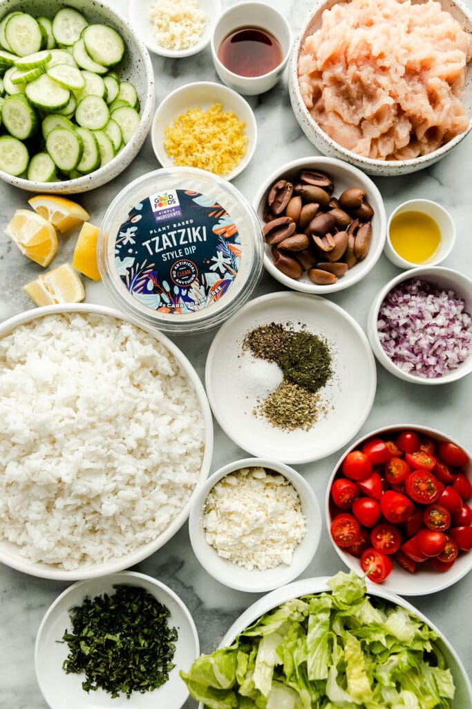 All ingredients for Greek chicken meatballs and salad bowls arranged in small bowls.