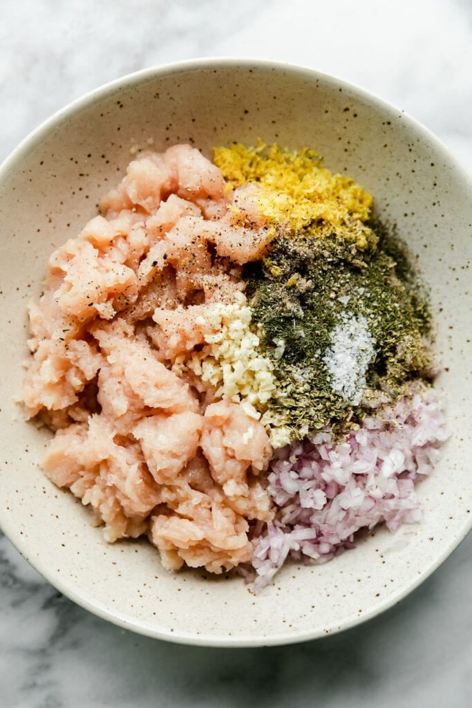 Ingredients for Greek chicken meatballs in stone bowl ready to be mixed together