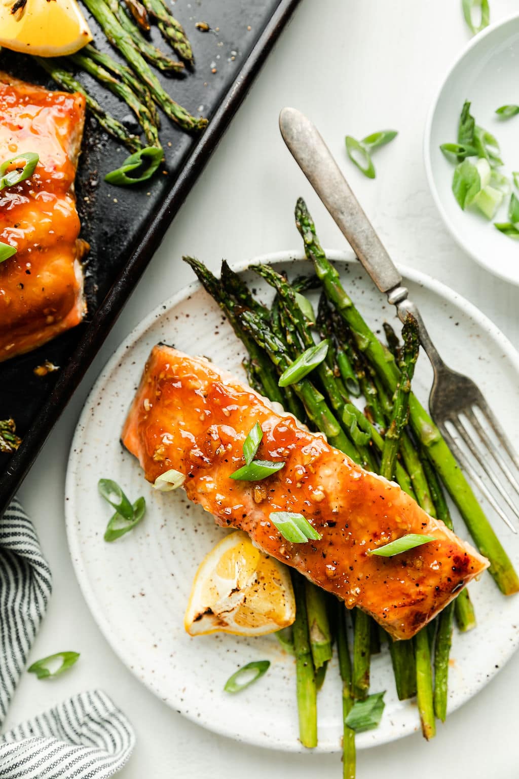 Stone plate with serving of honey glazed salmon filet and roasted asparagus, lemon wedge on the side.