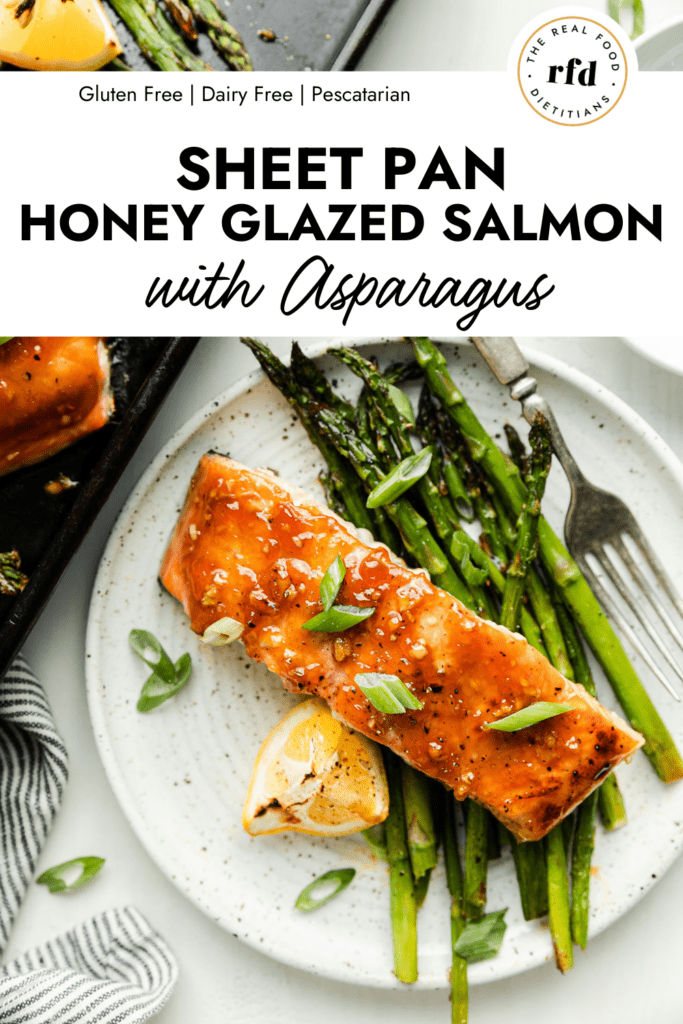 Honey glazed salmon filet on stone plate with roasted asparagus and lemons.