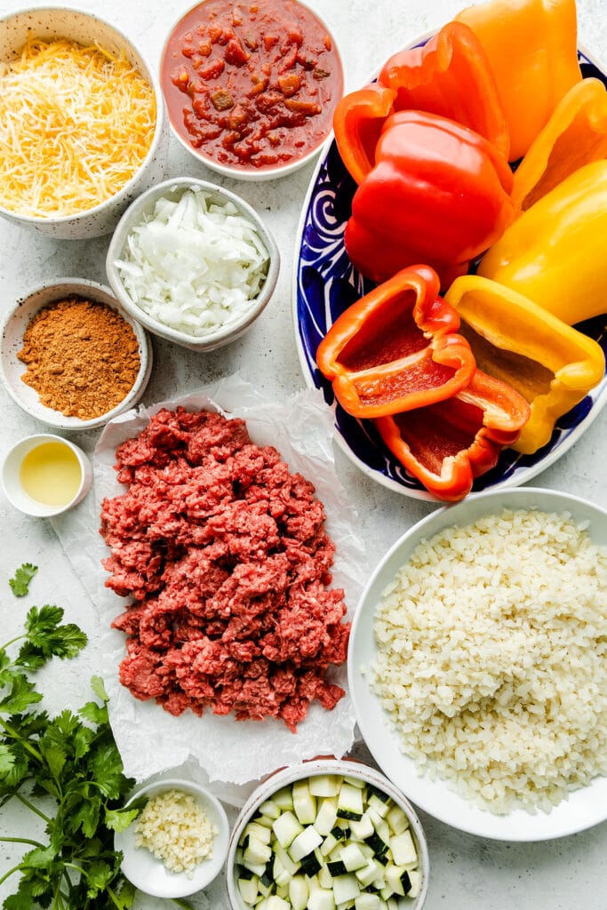 Ground meat, halved peppers, spices, diced onions, and other ingredients to be made into stuffed peppers.