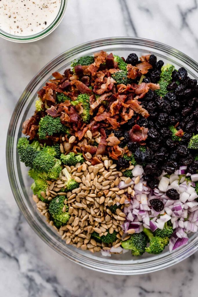 Overhead view broccoli salad ingredients in mixing bowl ready to stir together