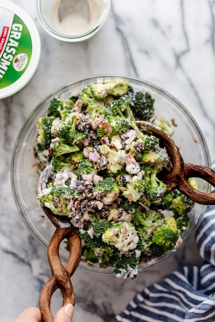 Creamy broccoli salad in mixing bowl with wooden spoon in salad
