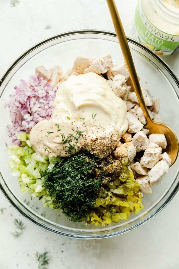 Overhead view all ingredients for dill pickle chicken salad in mixing bowl ready to be mixed together.