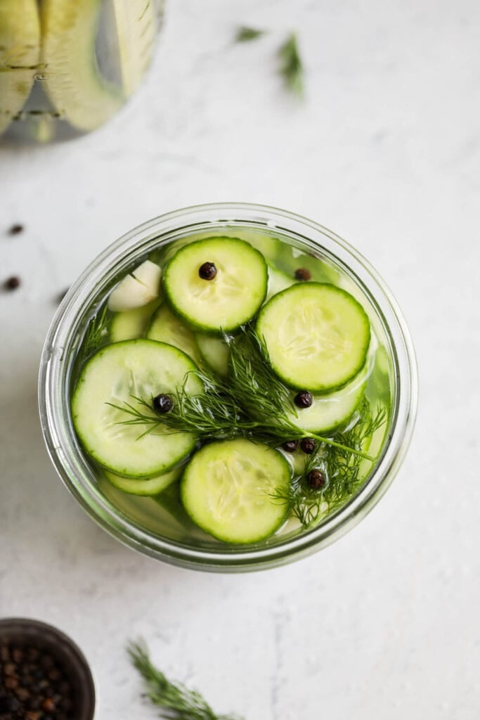 An overhead view of refrigerator dill pickle slices in a mason jar. 