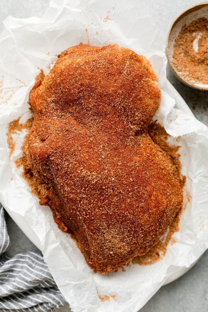 Overhead view pork loin rubbed with easy rub on parchment paper ready to be grilled.