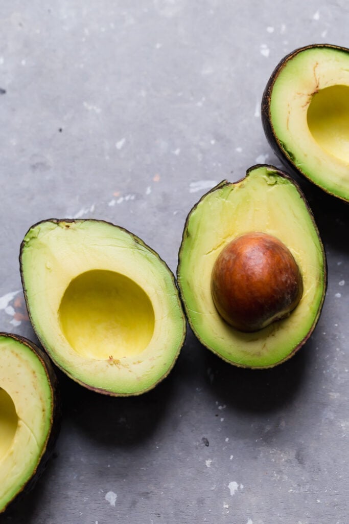 Ripe avocados sliced in half and ready to become guacamole.