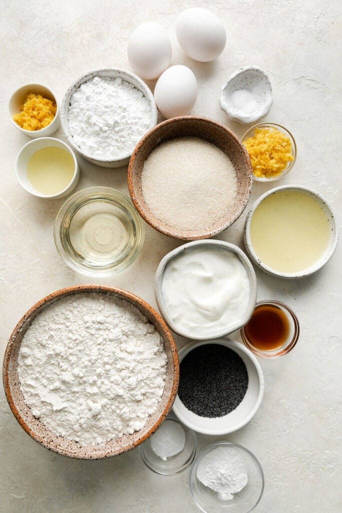 All ingredients for lemon poppy seed bread arranged together in small bowls.