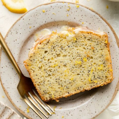 Overhead view slice of lemon poppy seed bread on stone plate.